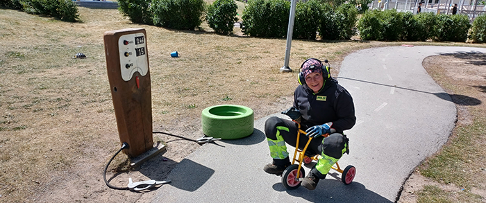 Slambilschaufför i arbetskläder som cyklar på en trehjuling